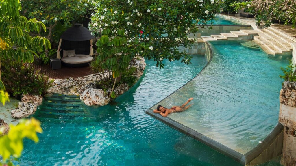 Winding river-style pool with planting and loungers